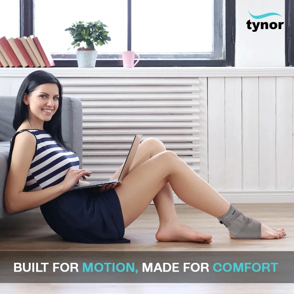 Woman sitting on the floor with a laptop, wearing the Tynor Ankle Support (Neoprene)