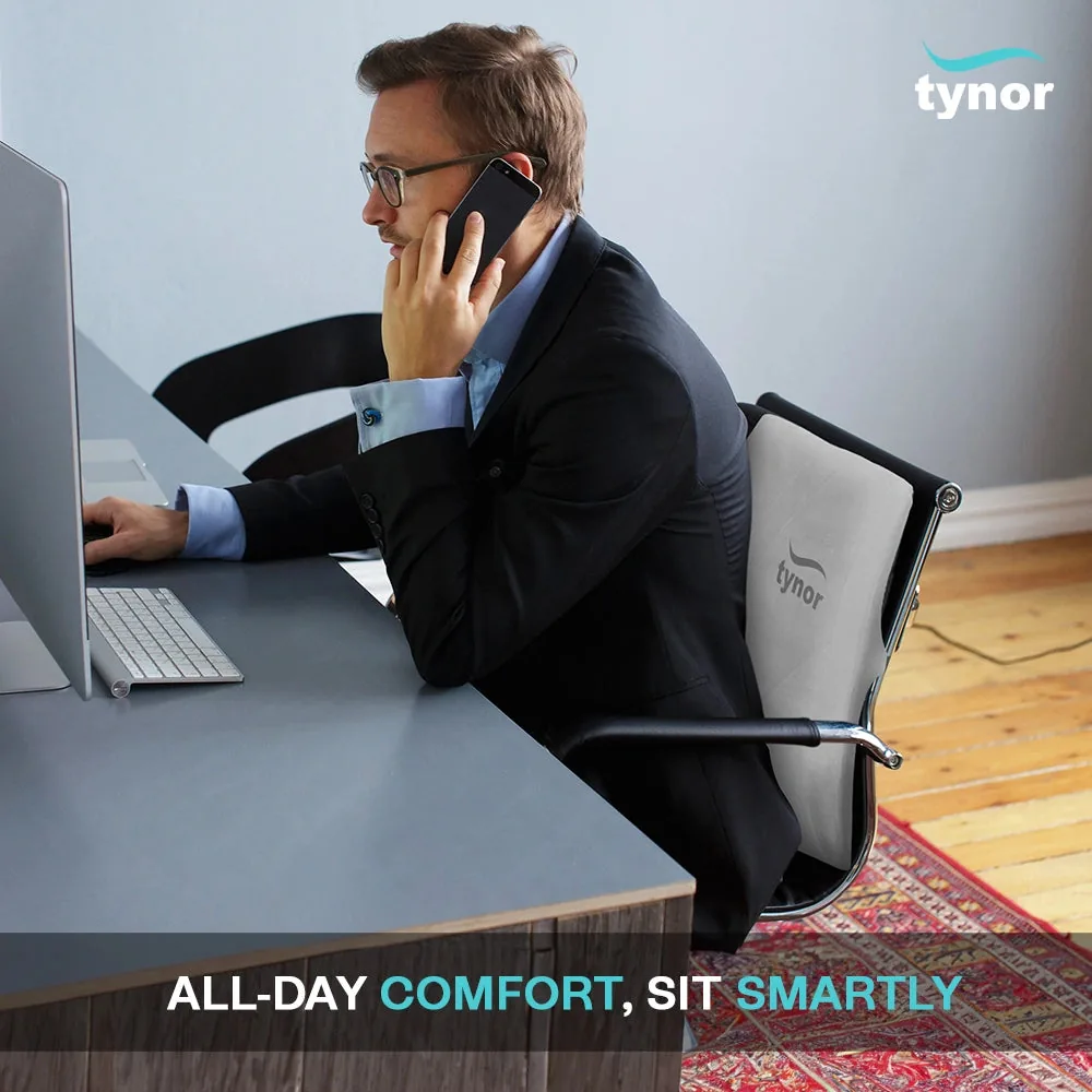 Man working at a desk on a phone call, with the Tynor Back Rest Full strapped to his office chair