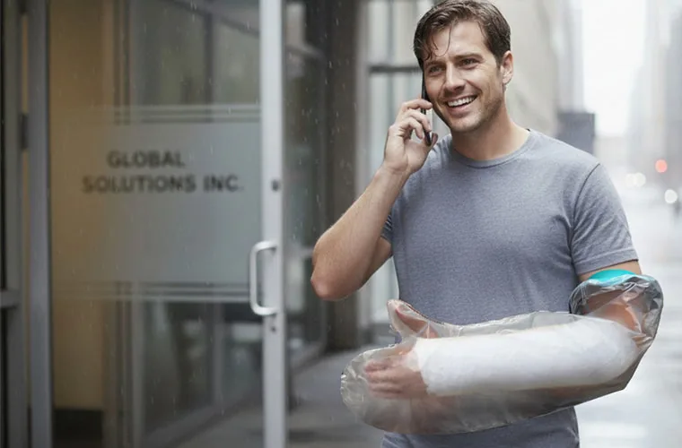 Man on a phone call in the city with his arm cast inside the Tynor Cast Cover Arm