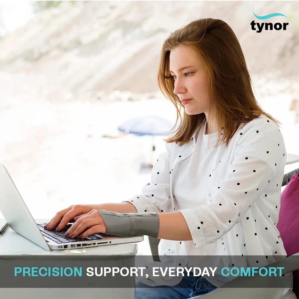 Woman typing on a laptop by the sea, wearing the Tynor Elastic Wrist Splint
