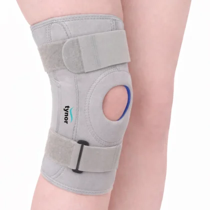 Tynor Knee Support Hinged (Neoprene) in grey worn on the knee, showing the patellar opening, side splint and straps