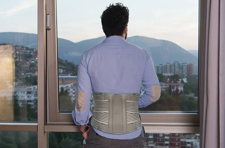 Man looking out of a window, wearing the Tynor L.S. Belt Lumbopore over his shirt