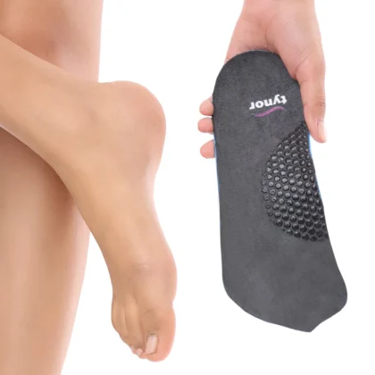 Tynor Medial Arch Orthosis insole held up beside a bare foot, showing the fabric top and honeycomb arch area