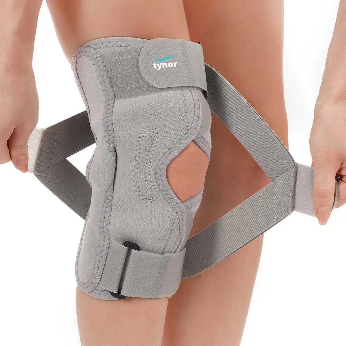 Tynor OA Knee Support (Neoprene) in grey, with its wrap-around straps being fastened around the knee