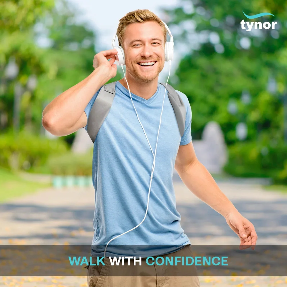 Smiling man with headphones walking in a park, wearing the Tynor Posture Corrector over a blue T-shirt