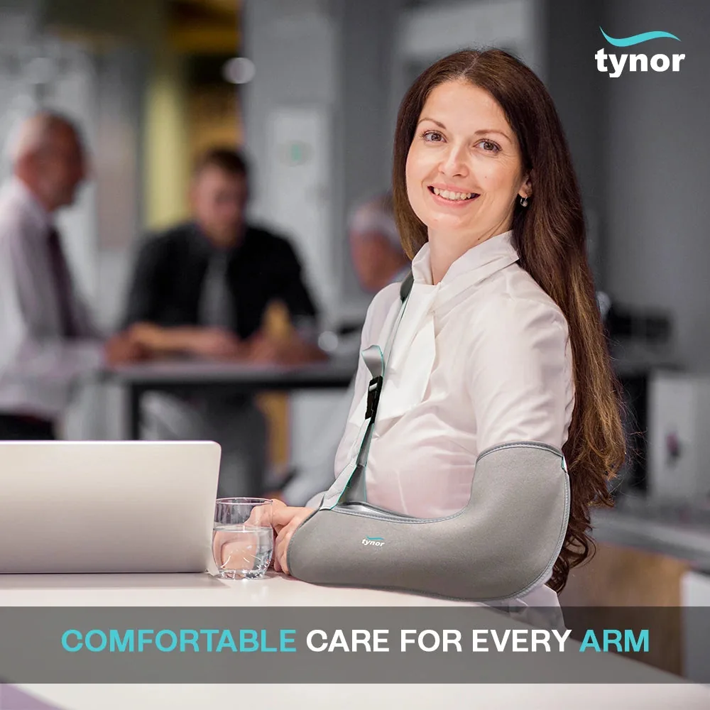 Smiling woman in a white blouse at an office desk, her forearm resting in the Tynor Pouch Arm Sling Tropical