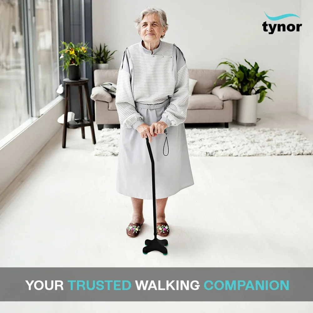 Older woman standing in her living room, resting both hands on the Tynor Quadra Stick