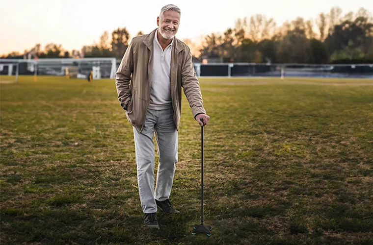 Older man walking across a field at sunset with the Tynor Quadra Stick