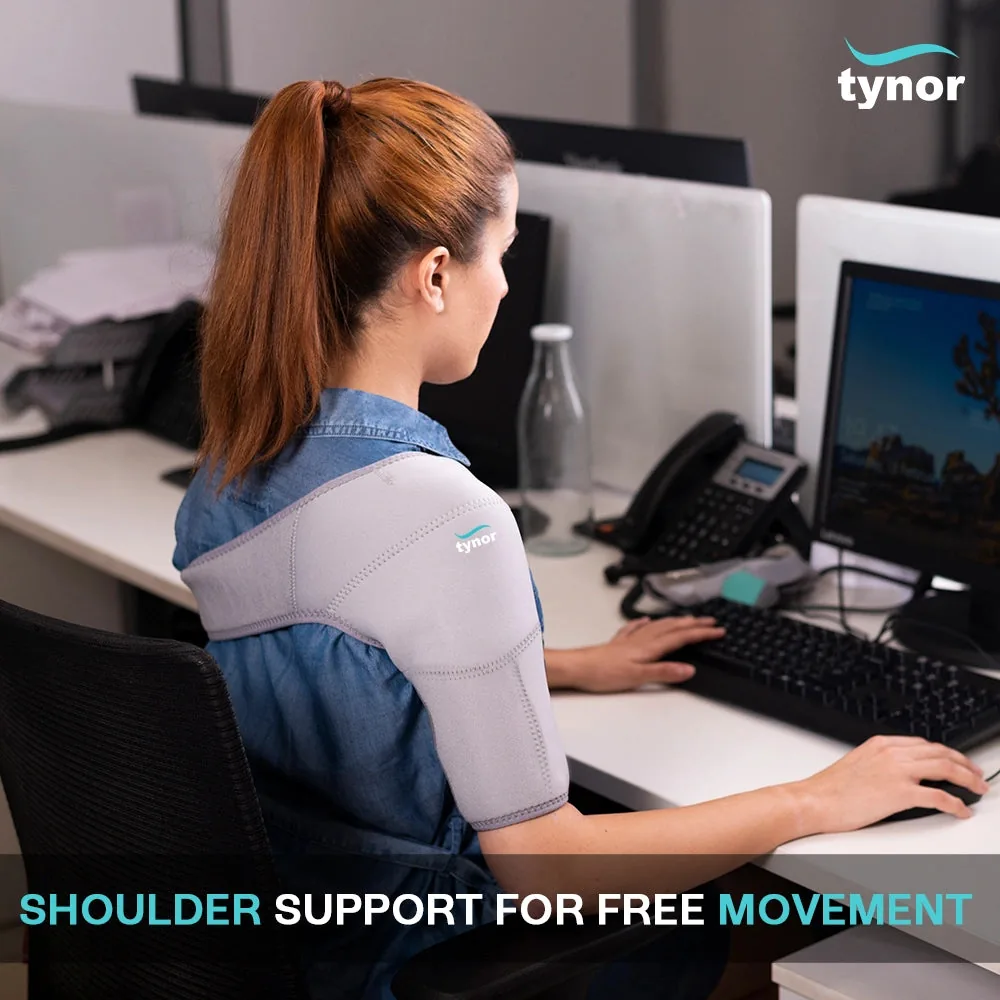Woman in a denim shirt typing at an office desk, wearing the Tynor Shoulder Support (Neoprene) on her shoulder