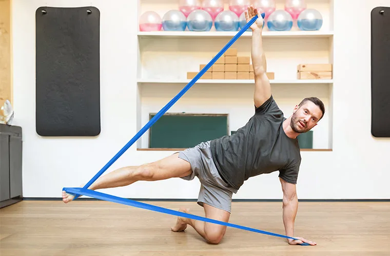 Man exercising with a blue Tynor Tyroband in a home gym