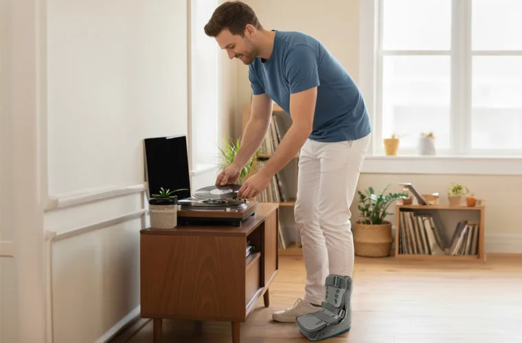 Man leaning over a record player at home, wearing the Tynor Walker Boot Air Pro Short