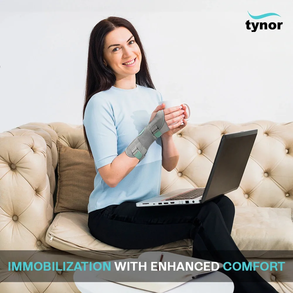Smiling woman on a sofa with a laptop and mug, wearing the Tynor Wrist & Forearm Splint