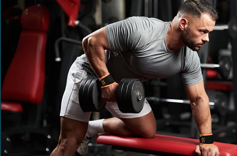 Man doing a one-arm dumbbell row on a gym bench, wearing the Tynor Wrist Support (Neo)